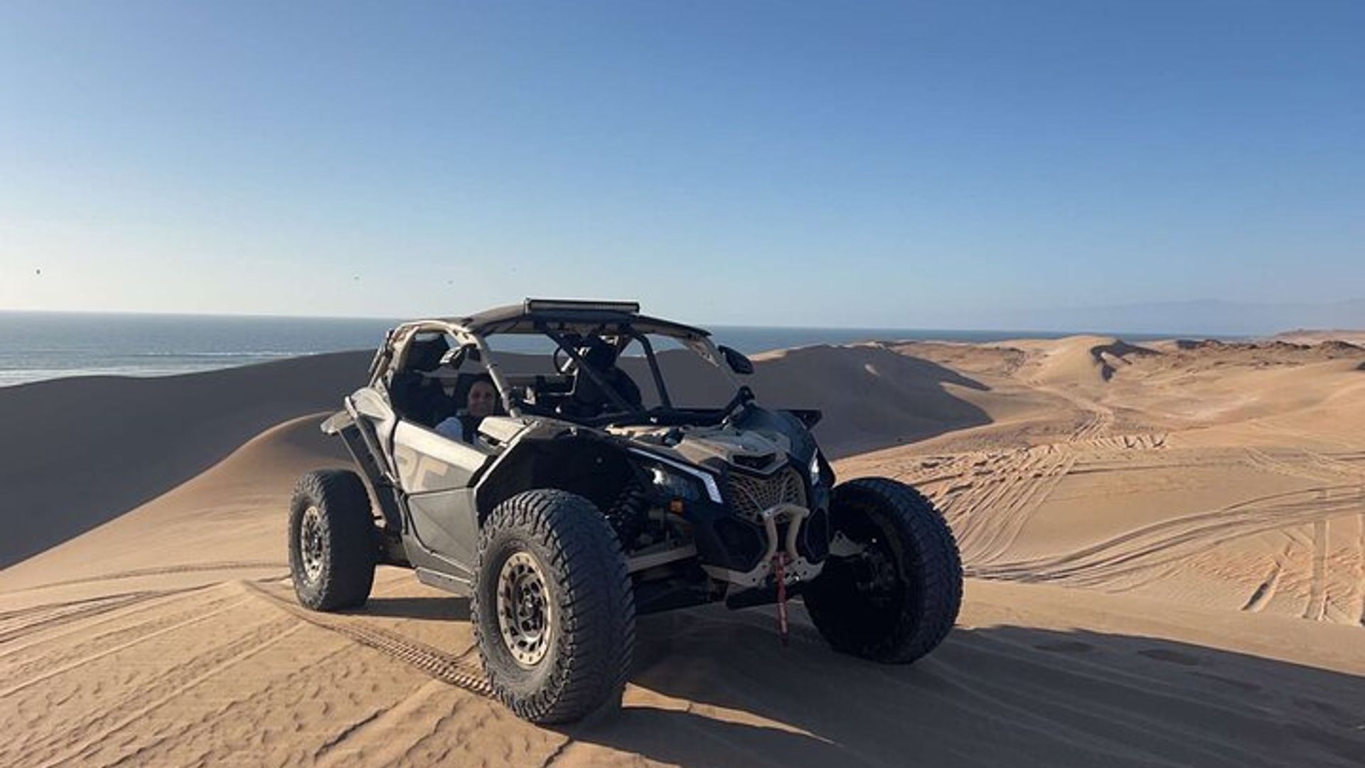 Buggy Can-Am Maverick en las dunas de arena, la playa y el bosque